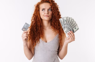 Thoughtful young woman with money in both hands