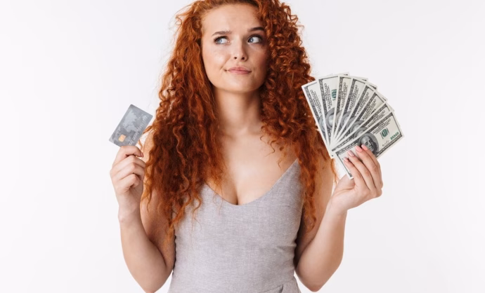 Mujer joven pensativa con dinero en ambas manos