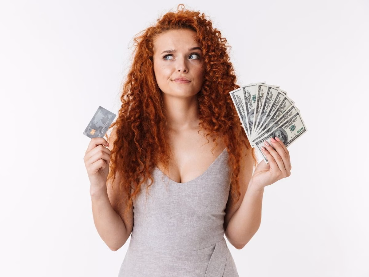 Thoughtful young woman with money in both hands