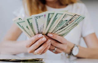 young woman's hands holding a lot of dollar bills