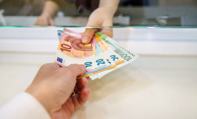 Mano de persona entregando dinero a otra persona