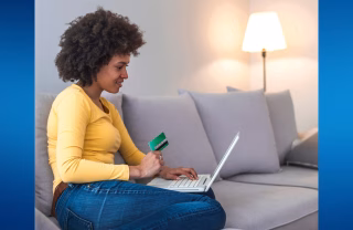 Woman sitting on a sofa making online payments with a laptop and card