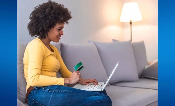 Woman sitting on a sofa making online payments with a laptop and card