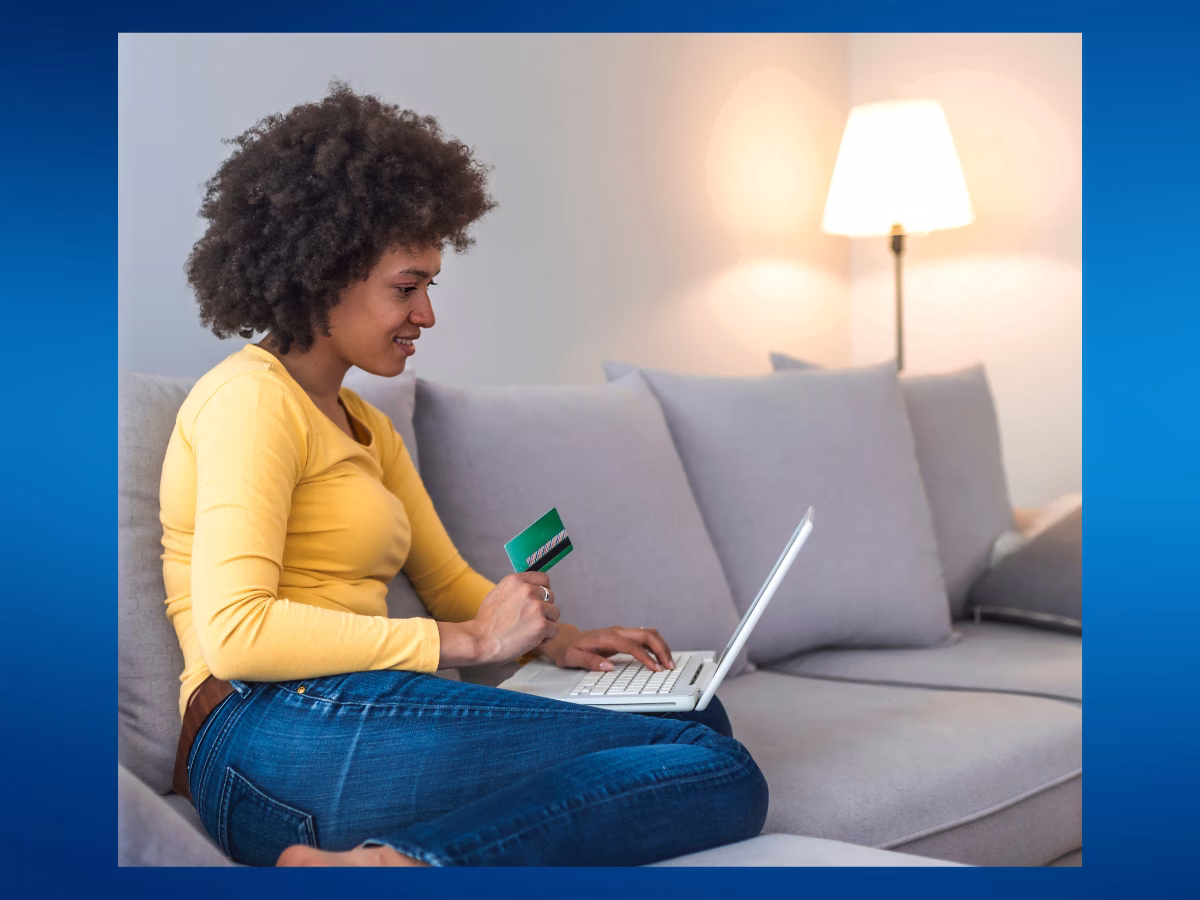 Woman sitting on a sofa making online payments with a laptop and card