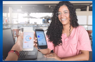 Young woman sending money from her phone to another phone