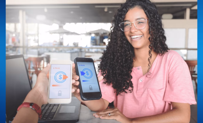 Young woman sending money from her phone to another phone