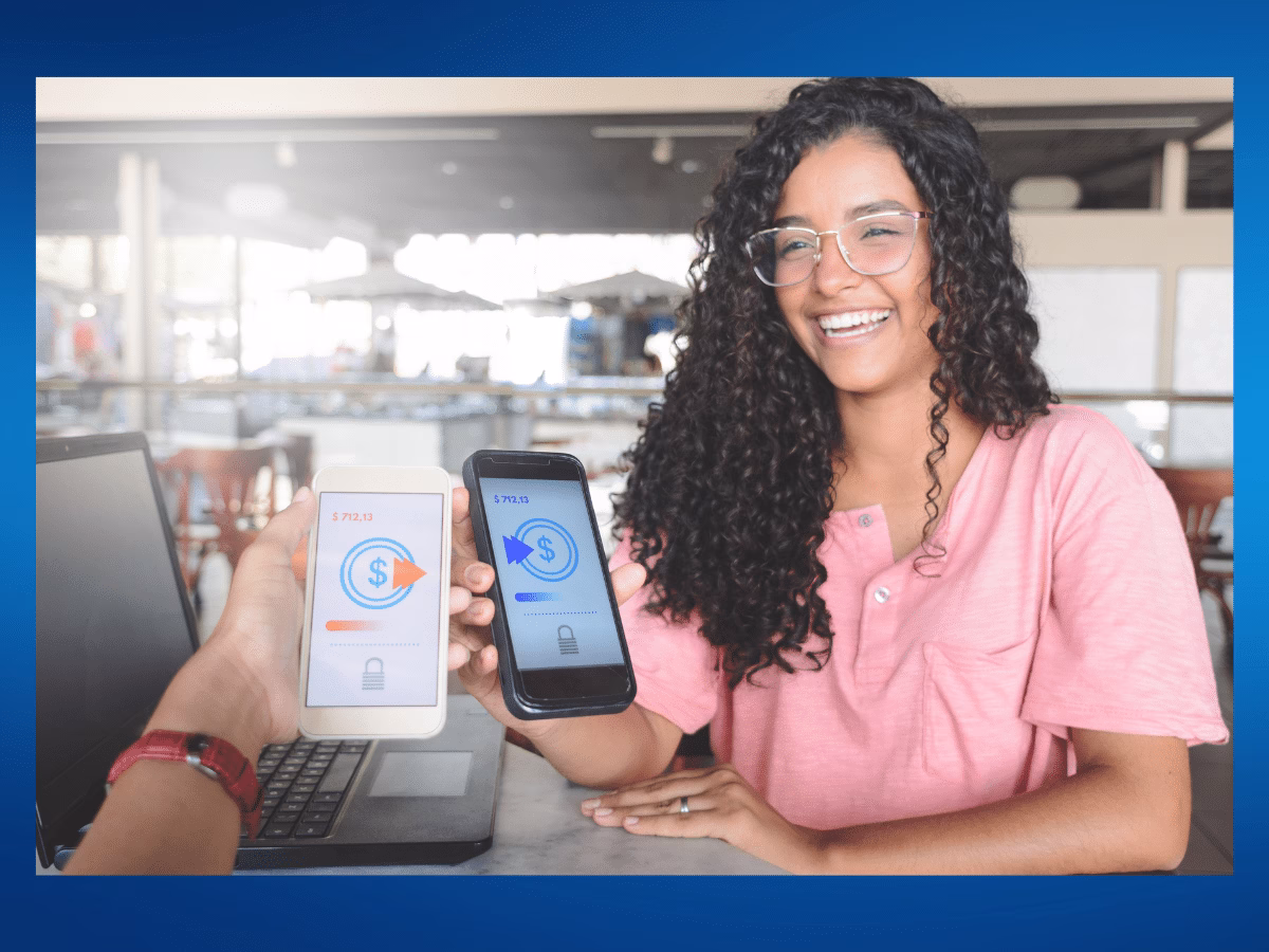 Young woman sending money from her phone to another phone